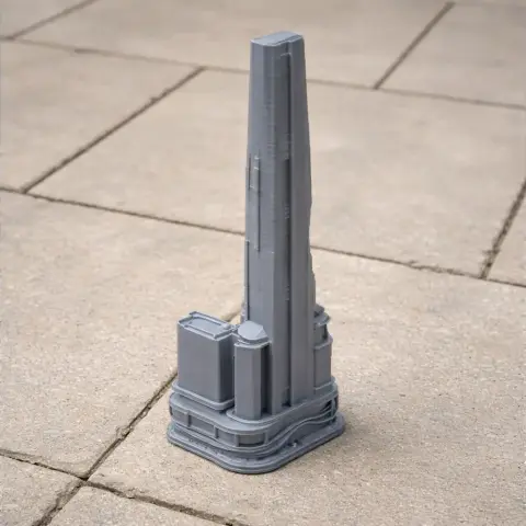 A detailed 3D printed model of a futuristic skyscraper with a tall central spire on a tiled surface.