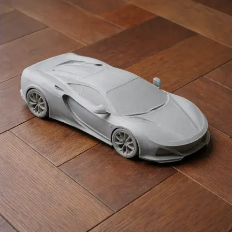 3D-printed model of a sleek sports car on a wooden surface.