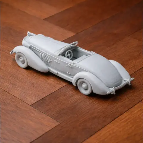 3D printed model of a vintage Auburn Speedster, detailed and grey, on a wooden surface.