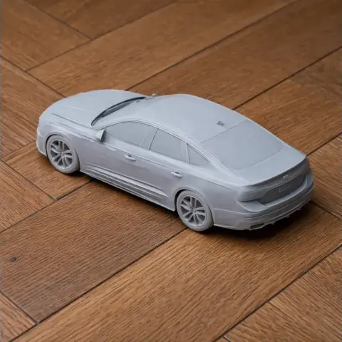 3D printed model of an Audi A4 car on a wooden surface.