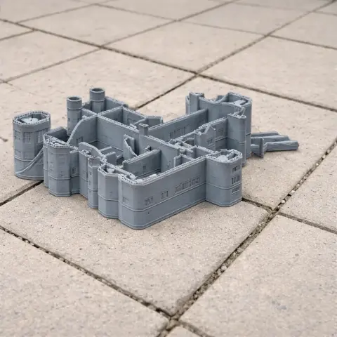 Gray 3D-printed architectural model of a castle with towers and detailed walls on a tiled surface.