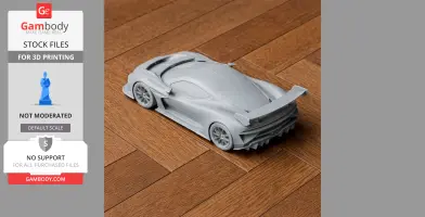 Gray 3D-printed Aston Martin Vulcan model on wooden surface, showcasing its sleek design and rear wing.