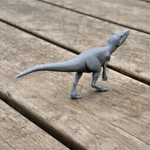 Gray 3D-printed model of Vectaerovenator, a prehistoric dinosaur, on a wooden surface.
