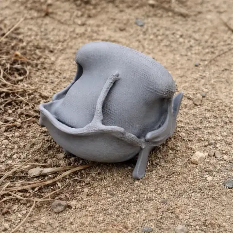 3D-printed gray gorilla skull replica resting on sandy ground.