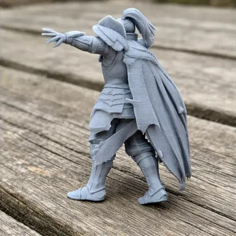 Samurai warrior figurine in armor, with extended arm and cape, on a wooden surface.
