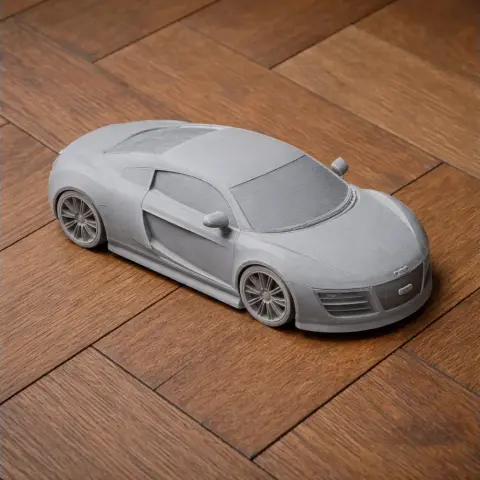 A detailed gray 3D printed model of an Audi Le Mans quattro on a wooden surface.