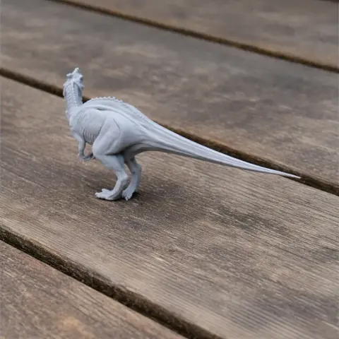 A 3D-printed model of a Yangchuanosaurus with a long tail, viewed from the side on a wooden surface.