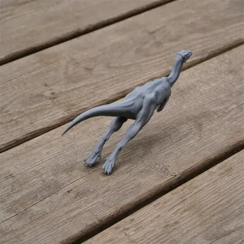 Gray 3D model of a Zephyrosaurus, a small dinosaur, on a wooden surface.