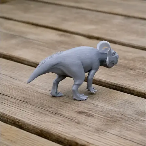 Gray 3D-printed model of a Zhuchengceratops dinosaur on a wooden surface.