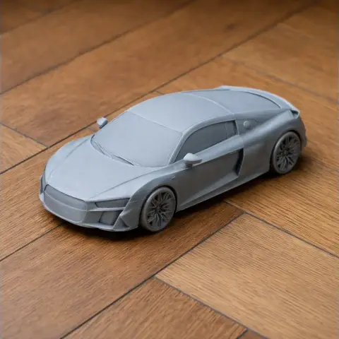 A gray 3D-printed model of an Audi R8 (Type 4S) on a wooden surface.