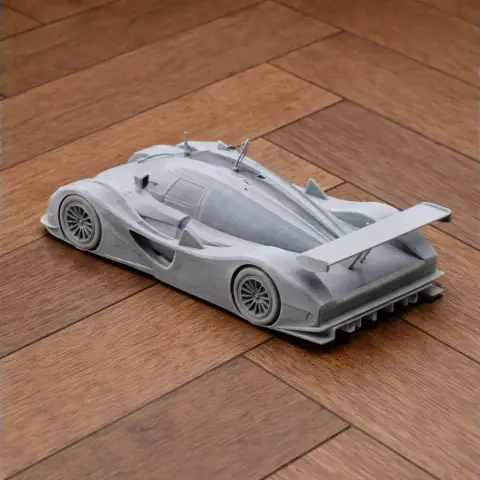3D printed model of a sleek Audi R8C race car on a wooden surface.