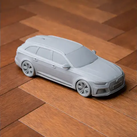 Gray 3D-printed scale model of an Audi RS4 vehicle on a wooden surface.