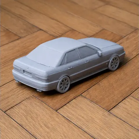 3D printed model of an Audi S2 vehicle on a wooden surface, rear side view.
