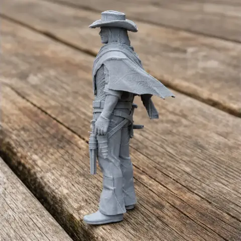 A 3D-printed model of a cowboy gunslinger with a hat and cape, standing on a wooden surface.