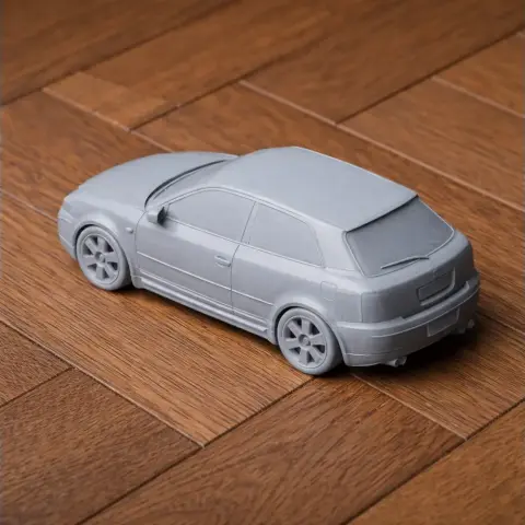 3D printed model of a gray Audi S3 car on a wooden surface.