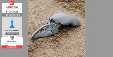 A 3D printed mammoth skull model lies on sandy ground with scattered dry grass.