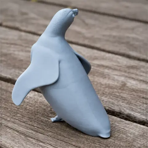 3D printed model of a penguin standing on a wooden surface.