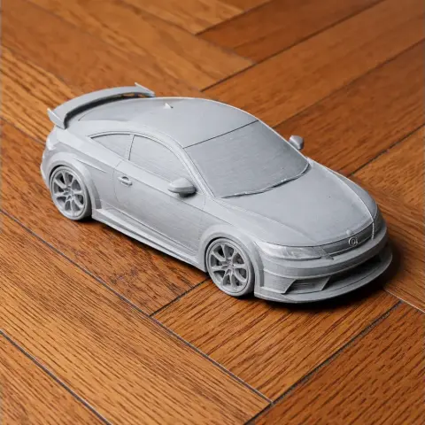 A 3D-printed gray Audi TT RS scale model on a wooden floor.