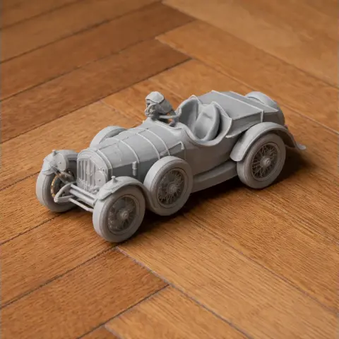 3D-printed vintage Austro-Daimler race car model with a driver on a wooden surface.