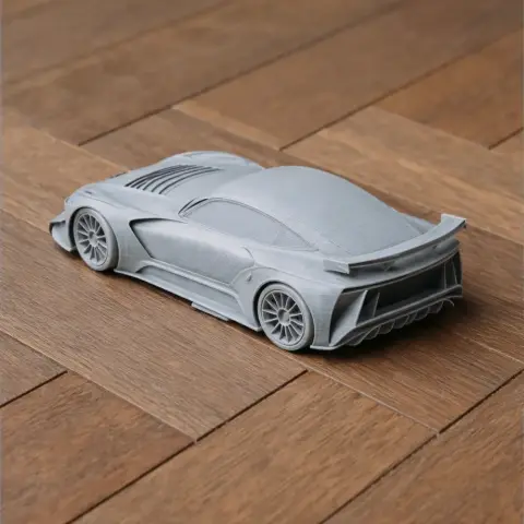 3D printed model of a sleek, futuristic sports car on a wooden surface.