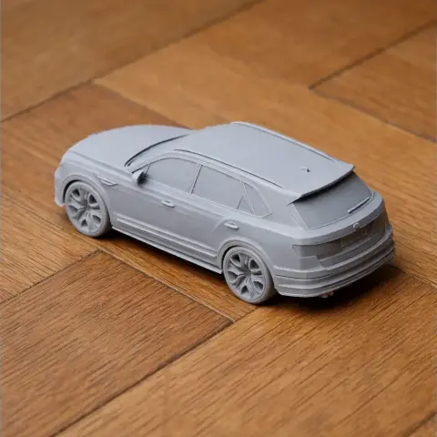 3D printed Bentley Bentayga model, gray, on a wooden surface. Side and rear view.
