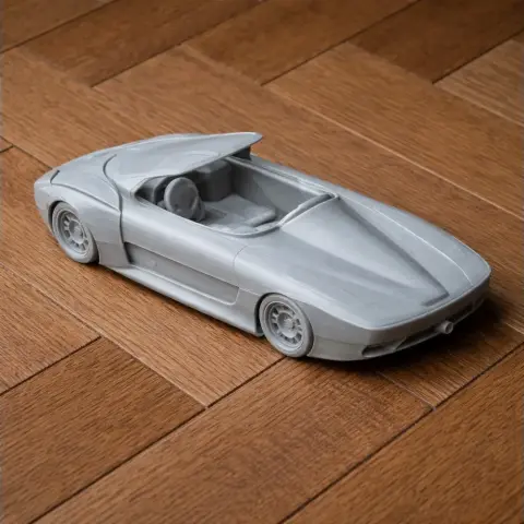 3D-printed model of a sleek, futuristic sports car on a wooden floor.