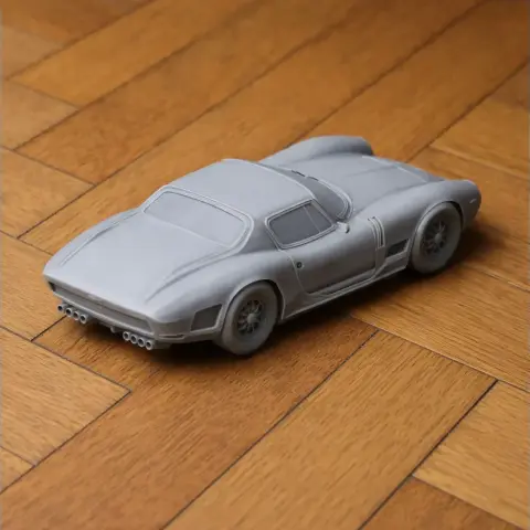 3D printed model of a Bizzarrini car, unpainted, on a wooden floor.