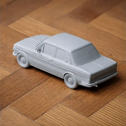 3D printed model of a classic BMW 2002 car on a wooden surface.