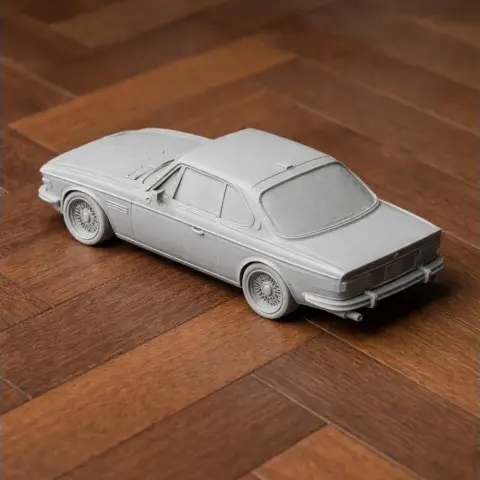 3D printed model of a classic BMW E9 car on a wooden surface.