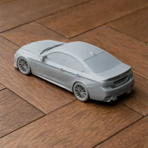 A 3D-printed model of a BMW E92 car in gray, displayed on a wooden surface.