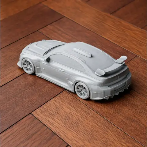 3D-printed BMW M2 racing model on wooden floor, showcasing detailed exterior and rear spoiler.