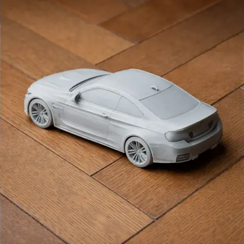 A detailed 3D printed model of a BMW M4 DTM car on a wooden surface.