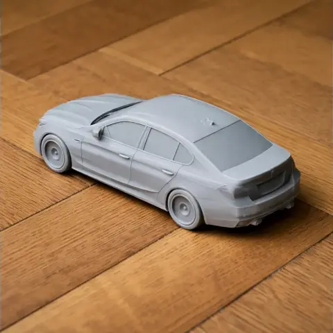 A 3D printed model of a BMW M5 car on a wooden surface.