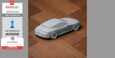 3D printed model of a sleek car on a wooden surface, from the rear side view.