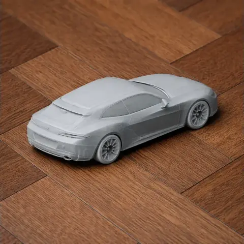 3D printed scale model of a sleek sports car on a wooden surface.