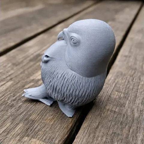 3D-printed figure of an owl with detailed feathers, perched on a wooden surface.