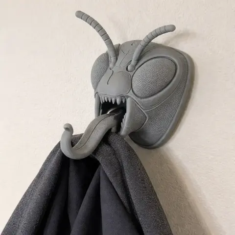 3D-printed wasp head wall hook with antennas and open mouth holding a coat.