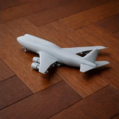 A gray 3D-printed model of a Boeing 747 on a wooden surface.