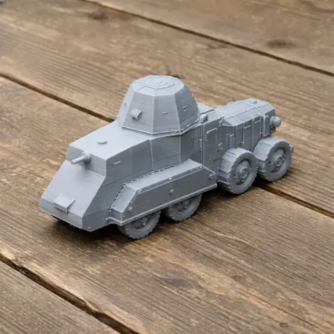 Gray 3D-printed model of an armored six-wheeled military vehicle on a wooden surface.