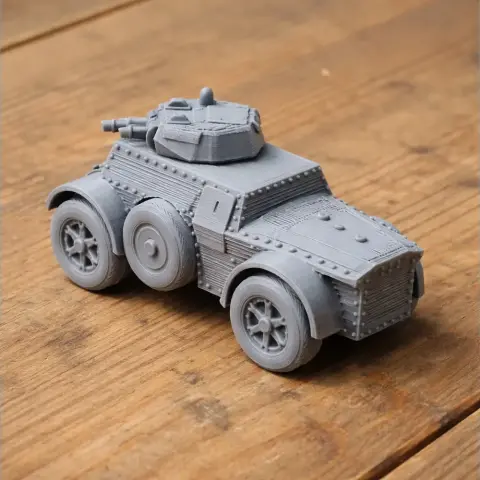 3D-printed model of an armored vehicle with detailed wheels and turret on a wooden surface.