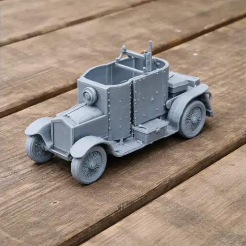 3D printed grey model of an early armored car, resembling vintage military vehicles, on wooden surface.