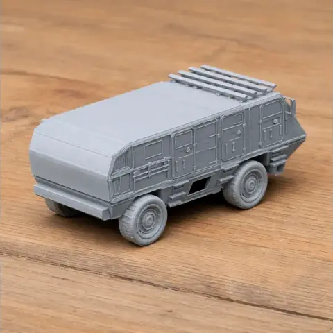 Gray 3D-printed model of a boxy armored vehicle with detailed texture and wheels on a wooden surface.
