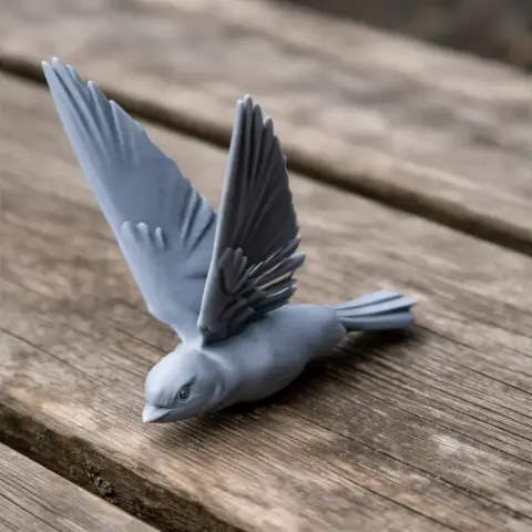 3D printed model of a bird with wings spread, on a wooden surface.