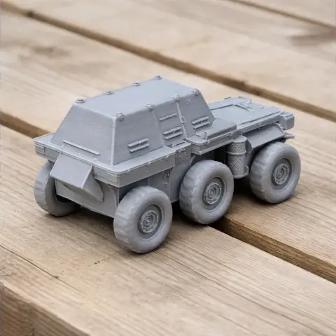 Gray 3D-printed military truck model with six wheels on wooden surface.
