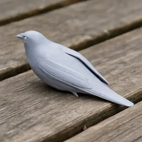 3D-printed model of a bird, resembling a warbler, placed on a wooden surface.