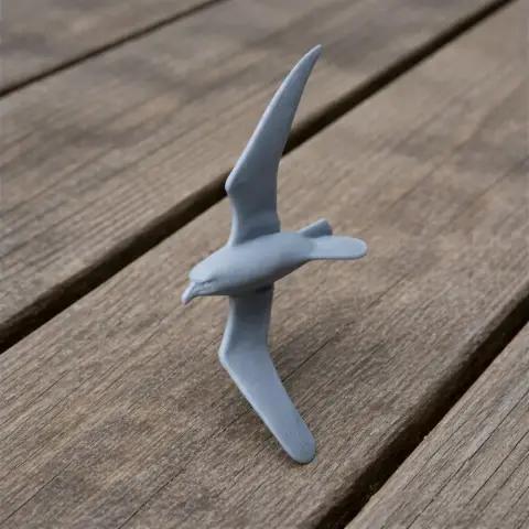 3D printed model of an Antarctic petrel bird in a dynamic flying pose on a wooden surface.