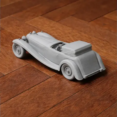 Gray 3D printed scale model of a Bugatti Royale car on a wooden surface.