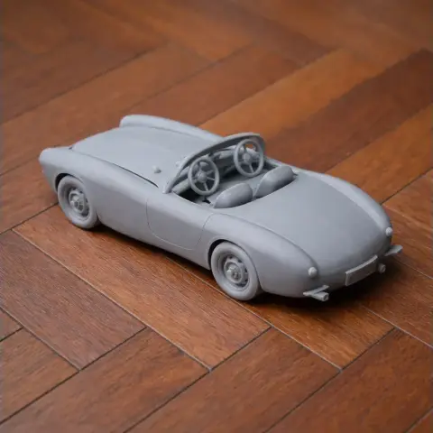 3D printed model of a Bugatti Type 252 car, gray, on a wooden surface.