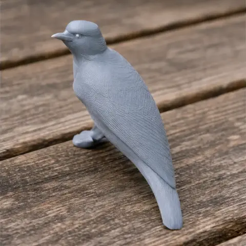 A gray 3D-printed model of a bird, posed standing with detailed feathers, on a wooden surface.