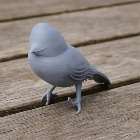 Gray 3D-printed model of a bird with detailed feathers, standing on a wooden surface.